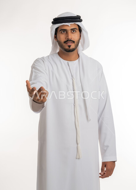 تعابير الجدية والرجولة، الترحيب والاستقبال بحب وبشاشة، بورتريه مقرب لرجل عربي خليجي امارتي يرتدي الكندورة والغترة ينظر الى شيء ما و يفتح كفه بإيماءات الثقة بالنفس، خلفية بيضاء