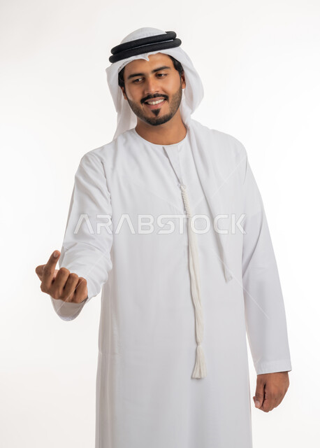 Indicating the location of an item, pointing and explaining something, specifying a specific location, portrait of an Arab Gulf Emirati man wearing a white kandura and ghutra pointing with his index finger to something, white background