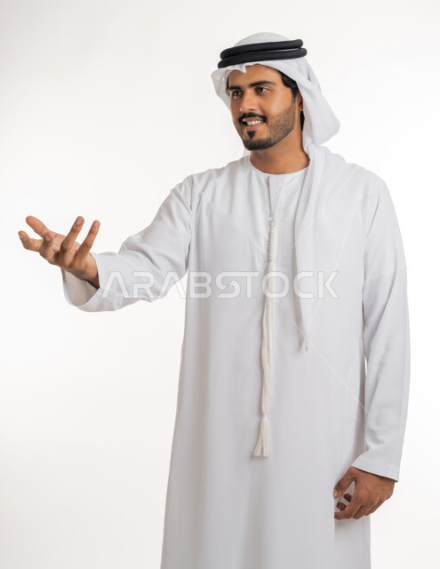 Trying to surround and grab something, pointing to an item, portrait of an Emirati Gulf Arab man wearing a kandora and ghutra, extending his hand forward trying to capture three-dimensional holographic elements, white background.
