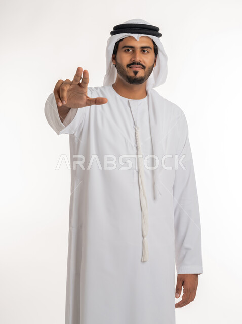 تحديد هدف معين، حركة اصبع وإشارات، الإشارة نحو الامام، بورتريه لرجل عربي خليجي إماراتي يرتدي الكندورة والغترة الإماراتية يشير باصابعه نحو شيء ما، خلفية بيضاء