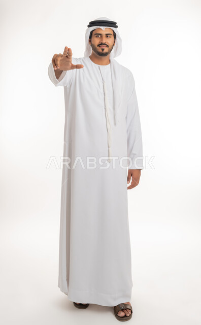 حركة اصبع وإشارات، الإشارة نحو الامام، بورتريه لرجل عربي خليجي إماراتي يرتدي الكندورة والغترة الإماراتية يشير باصابعه نحو شيء ما، تحديد هدف معين، صورة الجسم بالطول الكامل, خلفية بيضاء