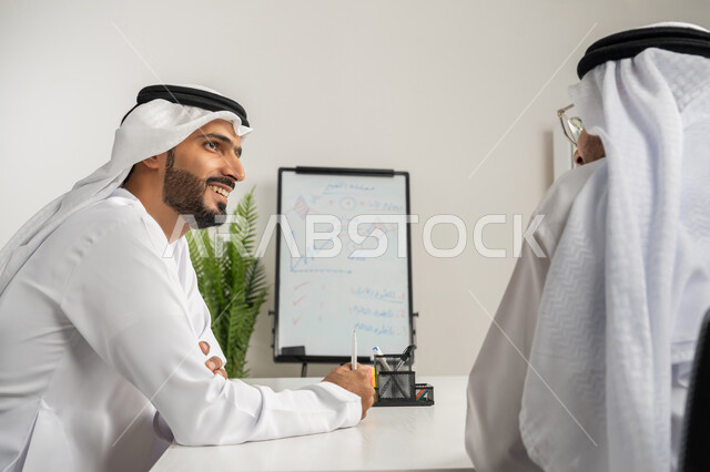 تبادل الأراء والافكار بين الموظفين، رجلان عربيان خليجيان إماراتيان يرتديان الغترة والكندورة يعقدان اجتماع داخل مقر الشركة، تعلم اساليب العمل والتطوير المهني، كتابة وتدوين الملاحظات، العمل الجماعي وروح الفريق الواحد، وضع الخطط الاستراتيجية لتحقيق الأهداف