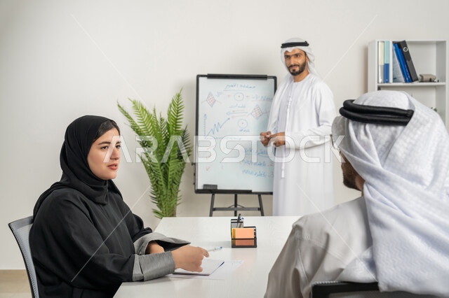 The concept of collaborative management, setting strategic plans to achieve goals, a group of Gulf Arab Emirati employees holding a meeting inside the company’s headquarters, learning work methods and professional development, administrative office jobs and professions, equality between men and women, teamwork and team spirit
