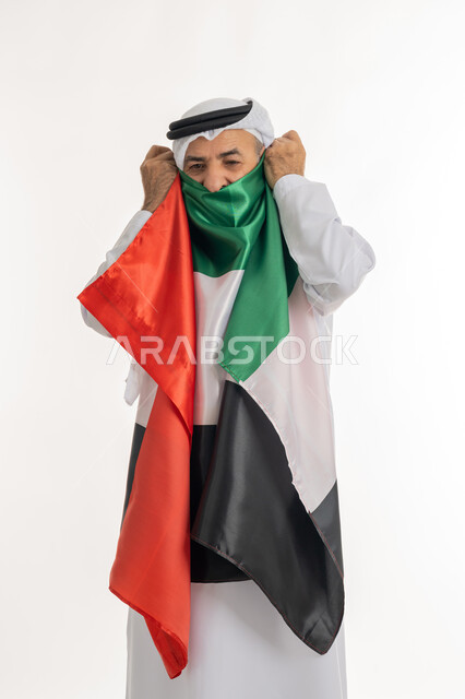 الاعتزاز والفخر بإنجازات الوطن، هوية اليوم الوطني الإماراتي 51، الإحتفال باليوم الوطني الإماراتي، يوم الاستقلال، الحب والانتماء للوطن، بورتريه لرجل عربي خليجي إماراتي يرتدي الكندورة والغترة البيضاء يقوم بتقبيل علم الإمارات العربية المتحدة، خلفية