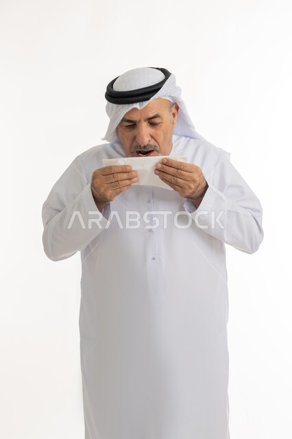 إيماءات الألم والتعب والمرض, بورتريه لرجل كبير السن عربي خليجي اماراتي يرتدي الغترة والكندورة يمسك المنديل بيديه ويغطي أنفه، ضرورة الحصول على الراحة وأخذ العلاج المناسب, العطاس والإحساس بأعراض الزكام والإصابة بالانفلونزا، خلفية بيضاء