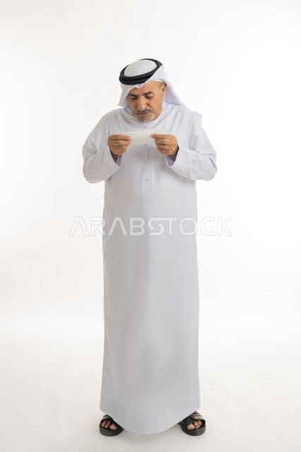 ظهور أعراض الانفلونزا والعطاس بشكل متكرر، ضرورة الحصول على الراحة وأخذ العلاج المناسب, الإصابة بالزكام والتعب والمرض, بورتريه لرجل كبير السن عربي خليجي اماراتي يرتدي الغترة والكندورة يمسك المنديل بيديه ويغطي أنفه، الجسم بالطول الكامل، خلفية بيضاء