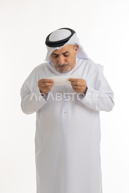 ضرورة أخذ العلاج المناسب والحصول على الراحة, العطاس والإحساس بأعراض الزكام والإصابة بالانفلونزا، إيماءات الألم والتعب والمرض, بورتريه  لرجل كبير السن عربي خليجي اماراتي يرتدي الغترة والكندورة يمسك المنديل بيديه ويغطي أنفه، خلفية بيضاء