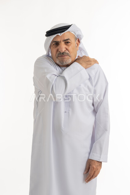 التهاب العضلات والمفاصل، بورتريه لرجل مسن عربي اماراتي خليجي يرتدي الكندورة و الغترة يضع يده على كتفه بتعابير الوجع، الحاجه لوضع خطة علاجية, طلب المساعده للذهاب الى المستشفى، الإحساس بالتعب والإرهاق, إيماءات الألم في الجسد، خلفية بيضاء