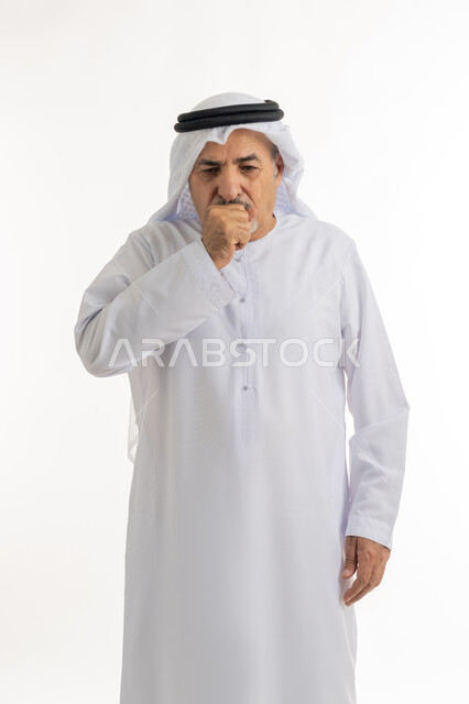 الإصابة بالتهاب الحلق وأمراض البلعوم، السعال بشكل متكرر بإيماءات الألم والتعب, بورتريه  لرجل كبير السن عربي خليجي اماراتي يرتدي الغترة والكندورة يغطي فمه بيديه ويكح، الحاجة للراحة وأخذ العلاج المناسب, خلفية بيضاء