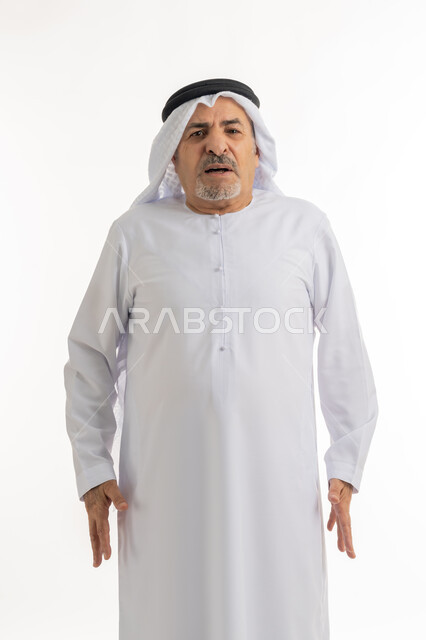 Looks of challenge and anger, portrait of an elderly Emirati Gulf Arab man wearing the Emirati ghutra and kandura, looking at the camera with gestures of discontent and grumbling, the concept of non-acceptance and dissatisfaction, feeling nervous and bored, frowning and annoyance expressions, white background