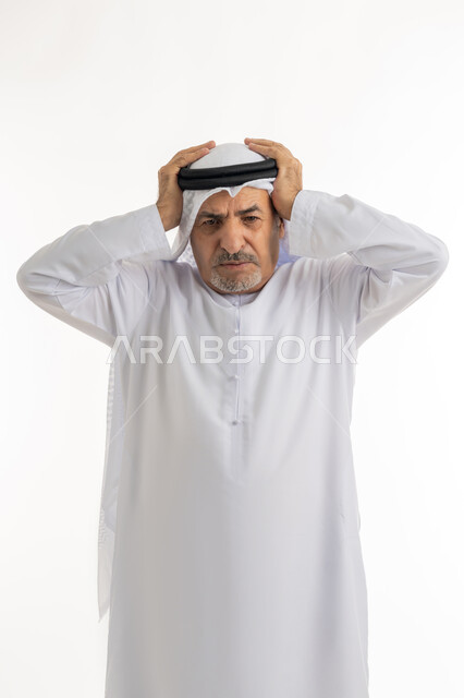 Feeling of headache and dizziness, need for treatment and rest, migraine and hemorrhoid pain, gestures of pain, fatigue and illness, portrait of an elderly Arab Gulf Emirati man wearing a ghutra and a kandura, putting his hands on his head feeling dizzy, white background