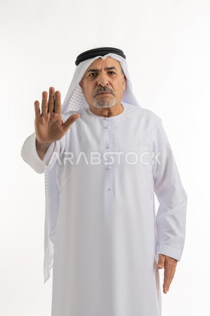 حركات الرفض و الامتناع, الوقوف باستقامة و اعتدال, بورتريه لرجل مسن عربي خليجي إماراتي يرتدي الكندورة والغترة يشير بكف يده للأمام لطلب التوقف وعدم الاقتراب، النظر إلى الكاميرا بتعابير الجدية و الحزم, خلفية بيضاء