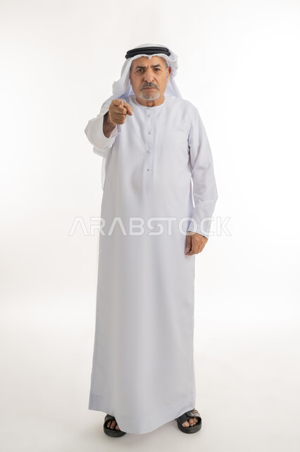 القاء اللوم و الاتهام، طلب التوقف عن فعل الأخطاء, بورتريه لرجل مسن عربي اماراتي خليجي يرتدي الكندورة و الغترة يرفع اصبع السبابة للاعلى لتحديد شخص ما ( أنت ), الشعور بالإنزعاج والرغبة بالإنتقام , صورة الجسم بالطول الكامل, خلفية بيضاء