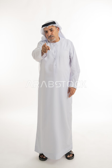 الشعور بالإنزعاج والرغبة بالإنتقام ,إلقاء اللوم و الاتهام، طلب التوقف عن فعل الأخطاء, بورتريه لرجل مسن عربي اماراتي خليجي يرتدي الكندورة و الغترة يرفع اصبع السبابة للاعلى لتحديد شخص ما ( أنت ), صورة الجسم بالطول الكامل, خلفية بيضاء