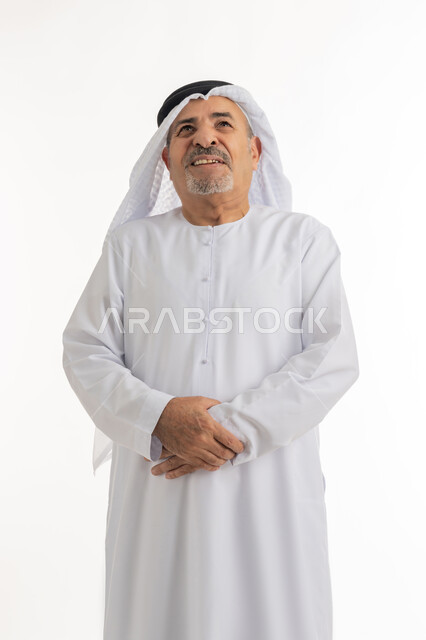 ضرورة الراحة وأخذ العلاج المناسب، الشعور بالمرض ووجع في البطن, حركات وجه ويدين تدل على الاضطراب والانزعاج، بورتريه لرجل كبير السن عربي خليجي إماراتي يرتدي الغترة والكندورة يضع يديه على بطنه بتعابير التألم, الجسم بالطول الكامل، خلفية بيضاء