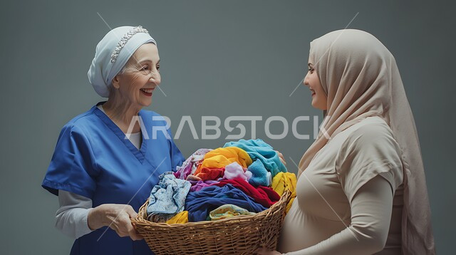 القيام بأعمال التنظيف والترتيب اليومية, المهام المنزلية الروتينية, مهن ووظائف نسائية في السعودية, استقدام العمالة الأجنبية, بورتريه مقرب لعاملة نظافة مسنة ترتدي زي العمل تقف أمام إمرأة عربية خليجية سعودية محجبة وتحمل بيديها سلة الغسيل, خلفية رمادية