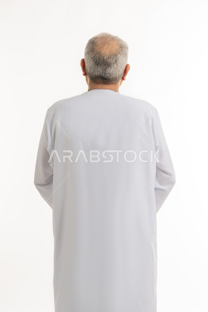 التقدم بالعمر والهيبة والوقار، بورتريه من الخلف لرجل كبير بالسن عربي خليجي إماراتي يرتدي الكندورة, الاهتمام بالأناقة والمظهر الخارجي، الوقوف باستقامة وثبات،  مفهوم الرجولة العربية, خلفية بيضاء