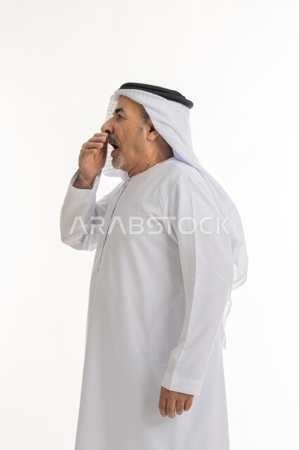 الحاجه الى النوم والراحه والإحساس بالإرهاق , بورتريه من الجانب لرجل كبير السن عربي خليجي اماراتي يرتدي الكندورة والغترة يضع يده على فمه بإيماءات تدل على النعاس, التثاؤب والشعور بالتعب و الكسل والخمول، خلفية بيضاء