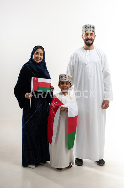 مناسبات واعياد وطنية, الفخر بإنجازات الوطن وثقافته, الاحتفال باليوم الوطني العماني 18 نوفمبر, إحياء ذكرى تأسيس الدولة 1775 م, بورتريه لرجل عربي خليجي عماني يرتدي الكمة والدشداشة يقف مع زوجته و ابنه يحتفلان بتوحيد السلطنة، الجسم بالطول الكامل، خلفية بيضاء