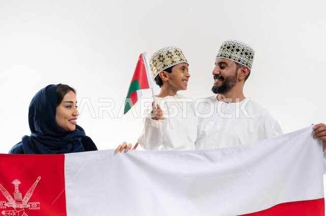 اعياد ومناسبات وطنية, الفخر بإنجازات الوطن وثقافته, الاحتفال باليوم الوطني العماني 18 نوفمبر, إحياء ذكرى تأسيس الدولة 1775 م, بورتريه لرجل عربي خليجي عماني يرتدي الكمة والدشداشة يقف مع زوجته و ابنه يحتفلان بتوحيد السلطنة، خلفية بيضاء