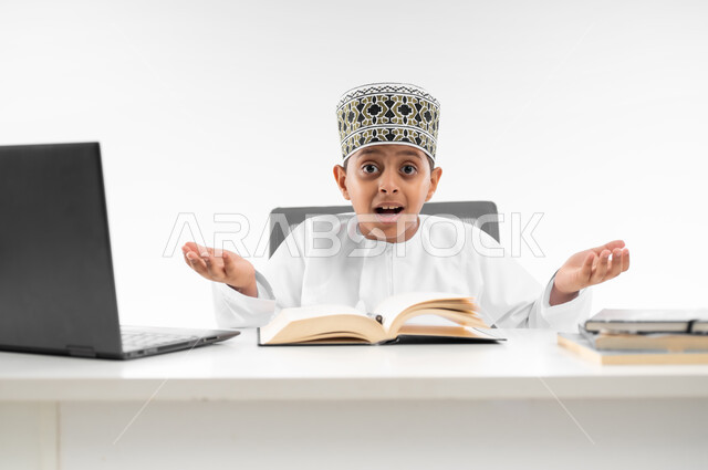 التردد وعدم الثقة بخصوص موضوع معين، استخدام الاجهزة التقنية الحديثة، بورتريه لصبي عربي خليجي عماني  يرتدي الدشداشة والكمة يرفع يديه بإيماءات عدم التأكد، مفهوم التعليم الإلكتروني، التساؤل والاستغراب والاستفسار من أمر ما، صورة لكامل الجسم، خلفية بيضاء