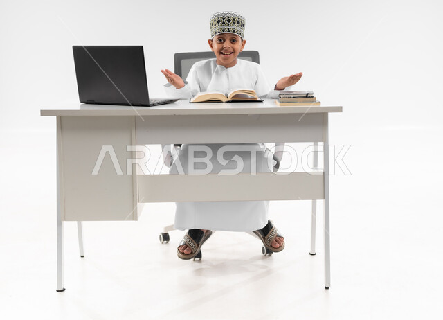 التردد وعدم الثقة بخصوص موضوع معين، استخدام الاجهزة التقنية الحديثة، بورتريه لصبي عربي خليجي عماني  يرتدي الدشداشة والكمة يرفع يديه بإيماءات عدم التأكد، مفهوم التعليم الإلكتروني، التساؤل والاستغراب والاستفسار من أمر ما، صورة لكامل الجسم، خلفية بيضاء