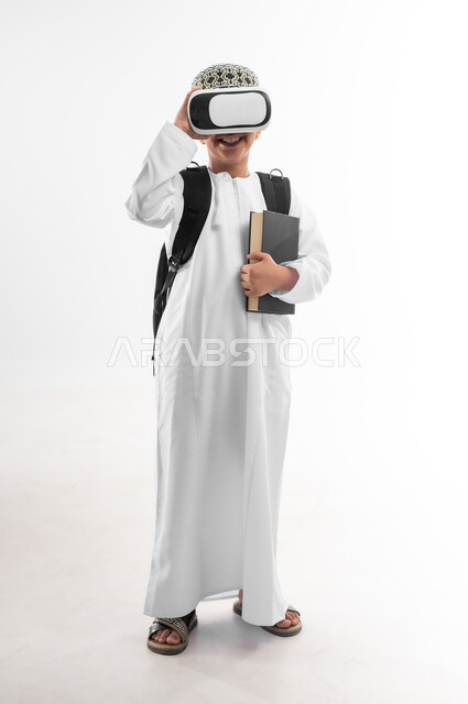 مدارس وأكاديميات متطوره، اتباع طرق تعليمية جديدة، بورتريه لتلميذ عربي خليجي عماني يرتدي الدشداشة والكمة يحمل الحقيبة المدرسية والكتاب يضع نظارات الواقع الافتراضي، جمع التعلم مع الترفيه، استخدام التقنيه والتكنولوجيا الحديثه، صورة لكامل الجسم، خلفيه بيضاء