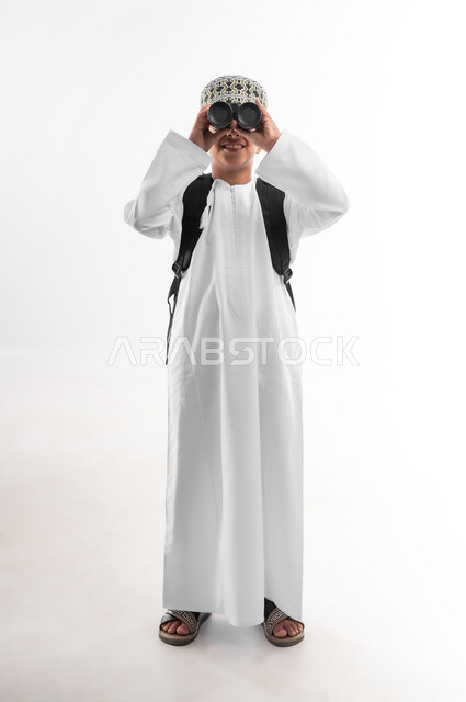 Love of exploration and adventure, seeing distant objects using a telescope, portrait of an Arab Gulf Omani student wearing a dishdasha and a kummah carrying a school backpack looking through a telescope, future planning for goals and ambitions, full body image, white background