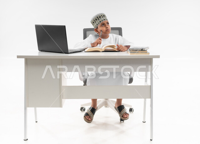 استخدام الاجهزة التقنية الحديثة، اللهو أثناء الدراسة، متابعة الحصص و حل الواجبات عبر الانترنت، بورتريه مقرب لصبي عربي خليجي عماني  يرتدي الدشداشة والكمة ينظر الى الاعلى بايماءات التفكير بشيء ما، مفهوم التعليم الإلكتروني، خلفية بيضاء