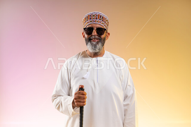 Teaching blind people mobility techniques using a cane, close-up portrait of an elderly blind Arab Gulf Omani man wearing a dishdasha and a kuma, wearing sunglasses and carrying a cane, providing psychological support to the blind, enhancing their confidence and motivating them to achieve their potential, colored background