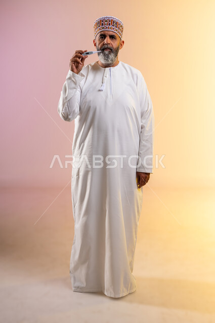 ضرورة زيارة الطبيب لوضع الخطة العلاجية، الإحساس بالمرض والإرهاق، بورتريه لرجل مسن عربي خليجي عماني يرتدي الدشداشه والكمه يقوم بقياس درجة حرارته بإستخدام الميزان الرقمي بتعابير الانزعاج والتعب، صورة الجسم بالطول الكامل, خلفية ملونة