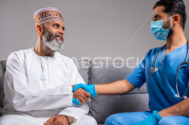 تقديم أفضل الخدمات الطبية لمرضى كبار السن، العمل في المجال الصحي، بورتريه مقرب لرجل عربي خليجي عماني مسن يرتدي الدشداشة والكمه يصافح الممرض بايماءات الامتنان، شكر وتقدير الطبيب لجهوده ورعايته الطبية، خلفية رمادية