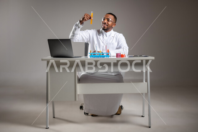 Conducting scientific experiments in a chemistry lab, portrait of a Saudi Arabian Gulf man wearing traditional dress and white coat, wearing safety glasses, holding test tubes, conducting research and reactions in educational laboratories, note taking concept, full body image, gray background