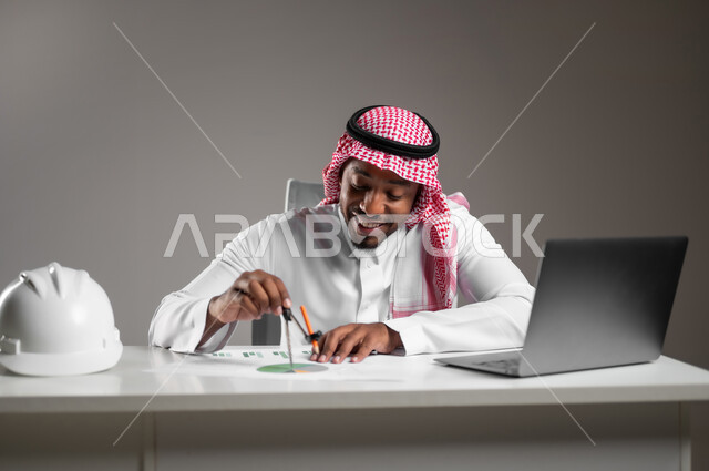Studying project basics, engineering project management, gestures of pleasure and happiness, integrating technology into work, working in engineering sector, close-up portrait of a Saudi Arabian Gulf engineer wearing traditional thobe sitting at desk checking and reviewing construction plans, gray background