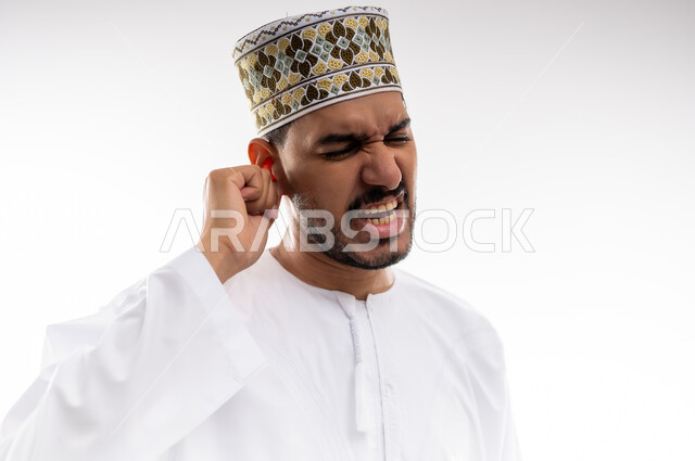 إلتهاب الاذن الحاد وضعف السمع، طلب العلاج والمساعده، بورتريه لرجل عربي خليجي عماني يرتدي الدشداشه والكمه يضع يده على أذنه بإيماءات تدل على الشعور بألم حاد في أذنه و الحاجه لزيارة الطبيب، خلفية بيضاء