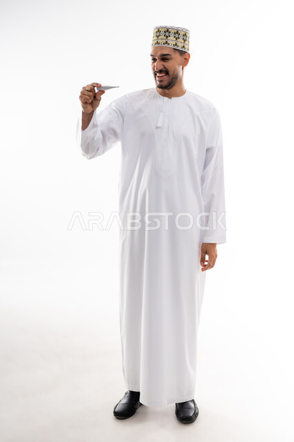 أعراض الاصابة بالحمى والتعب الجسدي وقياس درجه حراره الجسم،  بورتريه لرجل عربي خليجي عماني يرتدي الدشداشه والكمه يقوم بقراءه درجة حرارته باستخدام الميزان الحراري الرقمي, مفهوم الاهتمام بالصحة والحاجه الى العلاج, خلفية بيضاء