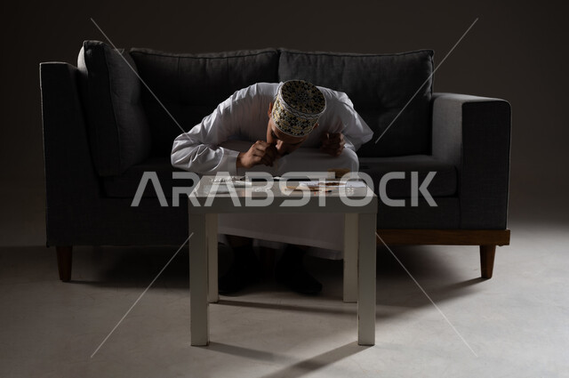 القيام بعادات سلوكية ضارة وتعاطي المواد السامة، الأثار السلبية للادمان على التبغ والمخدرات، المعاناة من الاضطرابات النفسية والمشاكل الصحية، بورتريه لرجل عربي خليجي عماني يرتدي الدشداشه والكمه يجلس على اريكة ويقوم باستنشاق المواد المخدره، صوره ظليه