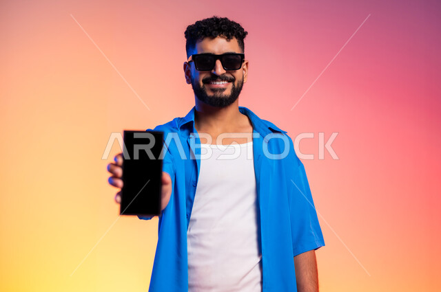 مفهوم اللياقة والرشاقة، المحافظة على التوازن الجسدي، امتلاك جسم رياضي صحي، الاهتمام بالمظهر الخارجي والأناقة، بورتريه لشاب عربي خليجي سعودي يرتدي الزي الكاجوال والنظارات الشمسية, ايماءات الثقة بالنفس، الطول الكامل للجسم، خلفية ملونة