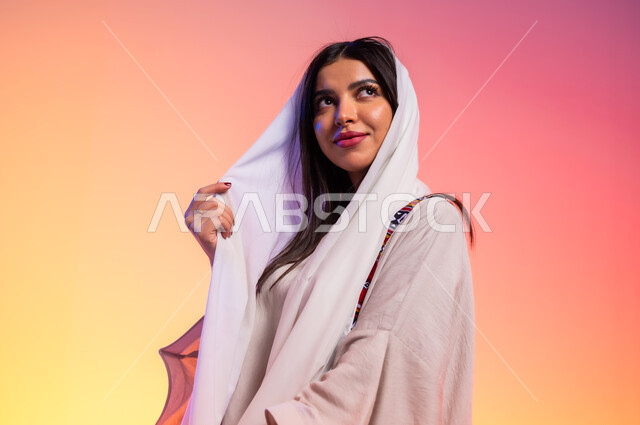 عرض الأزياء والموديلات الحديثة، ملامح الانوثة والنعومة, ألبسة خليجية نسائية عصرية، بورتريه مقرب لامرأة عربية خليجية سعودية ترتدي عباءة بيج تنظر إلى مكان ما بايماءات الخجل والحياء، مفهوم الموضة والأناقة، شراء الملابس والاكسسوارات الجديدة، خلفية ملونة