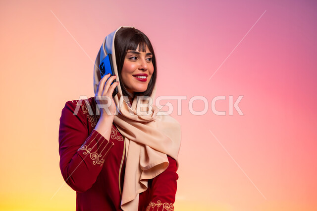 التواصل مع الاهل والاصدقاء باستخام الموبايل, ألبسة خليجية نسائية عصرية، بورتريه لامرأة عربية خليجية سعودية تحمل الهاتف المحمول وتقوم باجراء مكالمة هاتفية، مفهوم الموضة والأناقة، عرض الأزياء والموديلات الحديثة، شراء الملابس والاكسسوارات الجديدة، خلفية ملونة