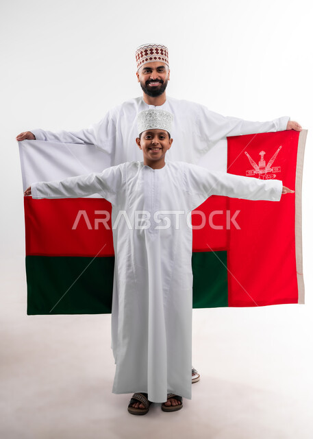 Celebrating Oman National Day, national flags and banners of Arab countries, pride in Omani symbols and banner, portrait of an Arab Gulf Omani boy and young man wearing a dishdasha and a kuma, the concept of love of the homeland and belonging to it, full body, white background