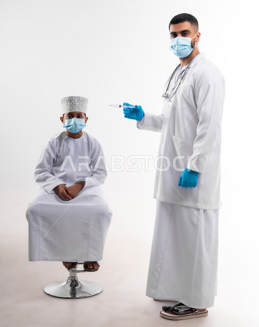 The availability of vaccination against the Corona virus for children, a portrait of a doctor wearing the coat and medical gloves, gives the dose of the Kofid vaccine - 19 to an Arab Gulf Arab child, adhering to safety procedures, following the laws of the Ministry of Health, body with full length, white background