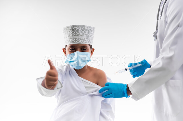 اتباع قوانين وزارة الصحة، اتاحة تلقي التطعيم ضد فايروس كورونا للاطفال، بورتريه مقرب لطبيب يرتدي المعطف والقفازات الطبية، يقوم باعطاء جرعة لقاح كوفيد - 19 لطفل عربي خليجي عماني، الالتزام بإجراءات السلامة، خلفية بيضاء