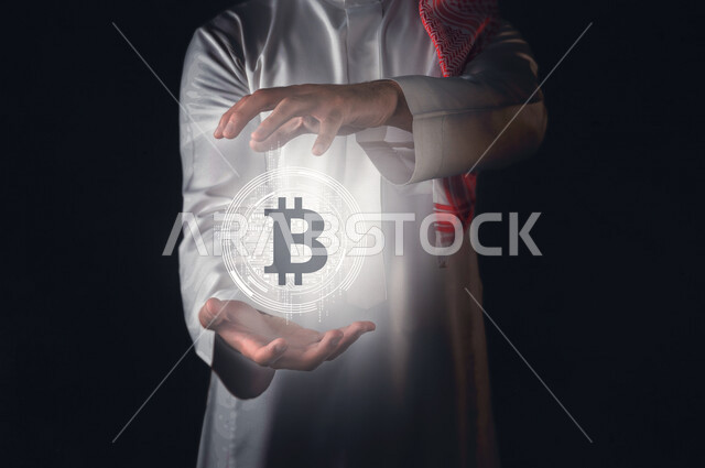 صورة مقربة لرجل عربي سعودي خليجي يحمل بين يديه شعار عملة البيتوكين بتقنية الهولوجرام ثلاثية الابعاد ، النمو و الأرباح المالية ، ادخار الأموال و تمويل الأعمال ، الفوائد و الاستثمار ، استخدم خاصية الهولوجرام ثلاثية الابعاد