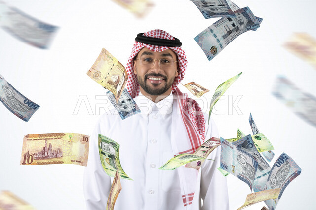 صورة مقربة لرجل عربي خليجي سعودي يبتسم لسقوط وتطاير مجموعة من الأوراق المالية السعودية ( الريالات ) ، ايماءات و تعابير تدل على السعادة ، مكافأت و علاوات مالية ،  جوائز و أرباح مالية و تجارية