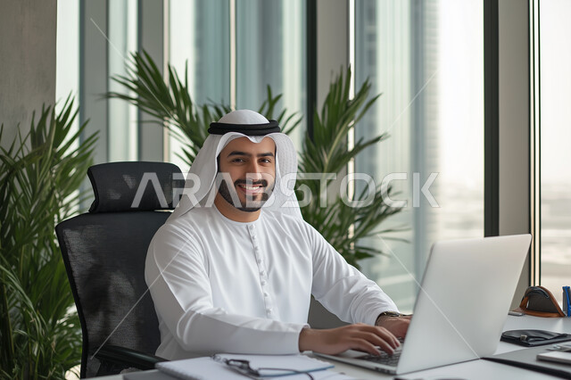 إدارة شؤون الأعمال وتنظيمها، صورة لرجل عربي خليجي سعودي مبتسم يقوم بالعمل على الحاسوب داخل المكتب، العمل لتحقيق الاهداف والاستراتيجيات، مهن ووظائف ادارية مكتبية, استخدام الأجهزة التكنولوجية الحديثة والمتطورة