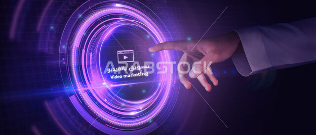 صورة مقربة ليد رجل عربي خليجي سعودي، يضغط بأصبعه على زر تسويق بالفيديو، التسويق الرقمي عن بعد عبر الانترنت، أيقونات خاصة بالكمبيوتر، إعلانات تسويقية، مفهوم تكنولوجيا شبكة الإنترنت، رموز رقمية الكترونية