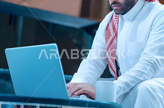 Completing projects and tasks, business and professions, following up and discussing work, holding a business meeting online, e-marketing, surfing the internet, close-up of a Saudi Arabian Gulf man using a laptop to complete tasks, business session