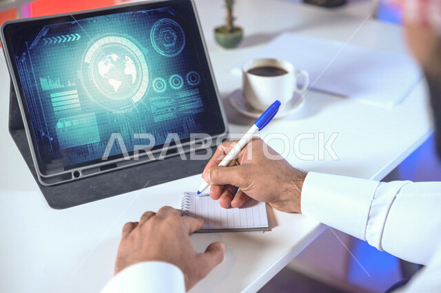 تصوير مقرب ليد رجل اعمال عربي خليجي سعودي يستخدم جهاز التابلت و يدون الملاحظات ،تكنولوجيا الاتصالات والانترنت في جميع انحاء العالم ، مفهوم تكنولوجيا الاعمال