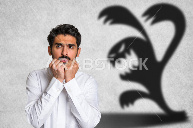 رجل عربي خليجي سعودي، تهيؤات وخيالات، ايماءات وجه تدل على الخوف والرعب مع خلفية تحتوي على رسومات مخيفة، مخاوف، التنمر، المشاكل النفسية